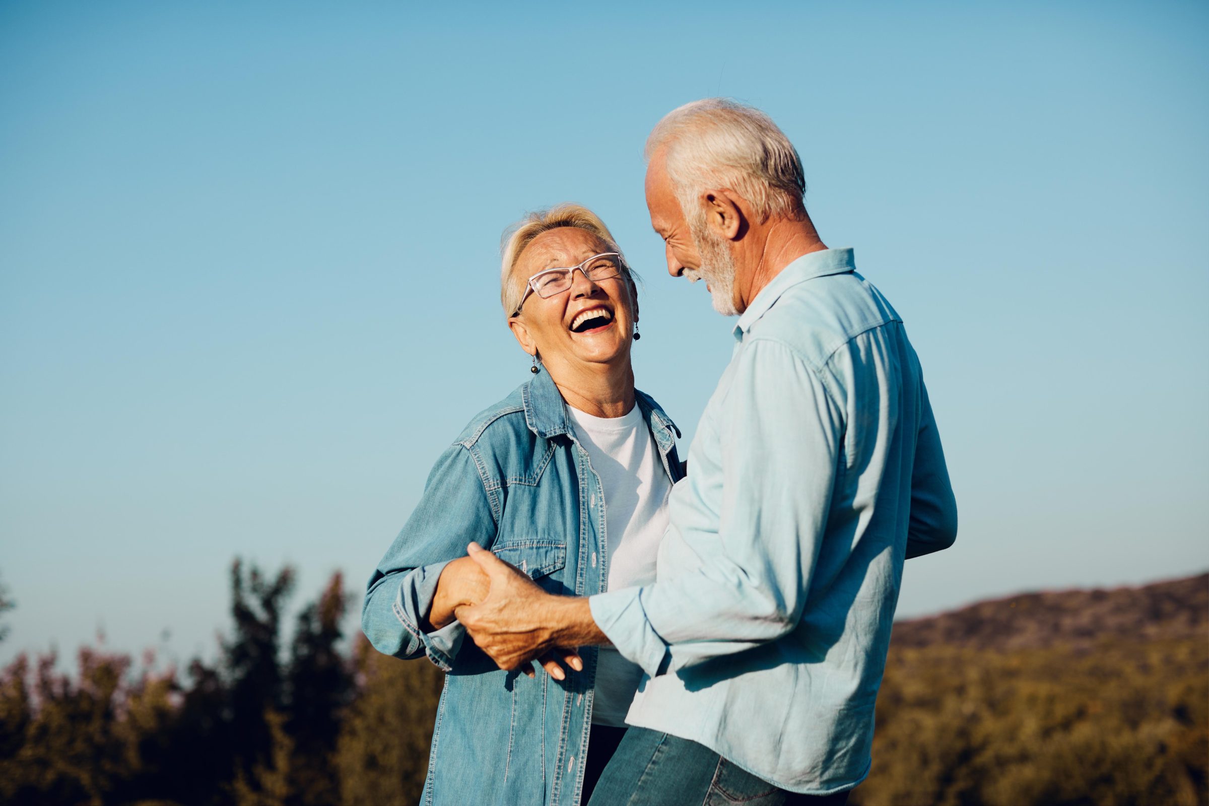 An older couple laughing together outdoors
