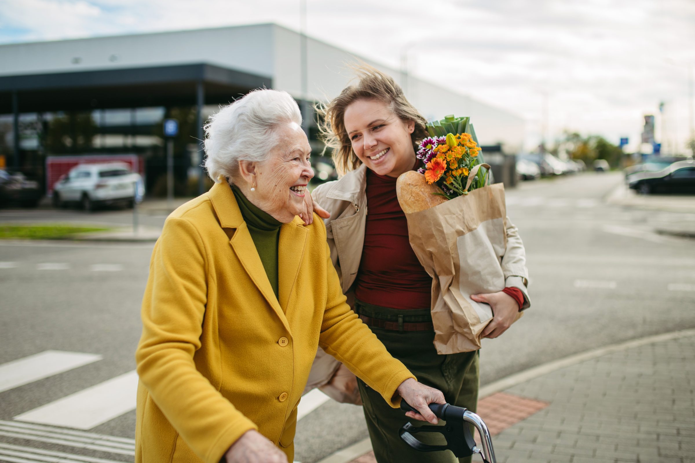 An older woman with a walker and her granddaughter carrying flowers
