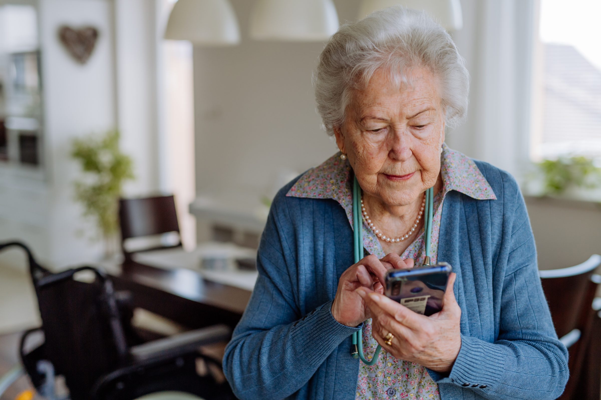 An older woman reading her phone at home